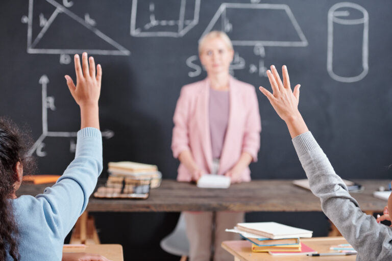 Arms of two clever schoolkids willing to answer question of teacher at lesson